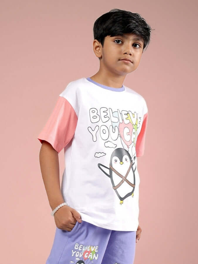 Young boy wearing a white-pink 'Believe You Can' T-shirt for kids, featuring a cute penguin illustration, designed by DUDS.