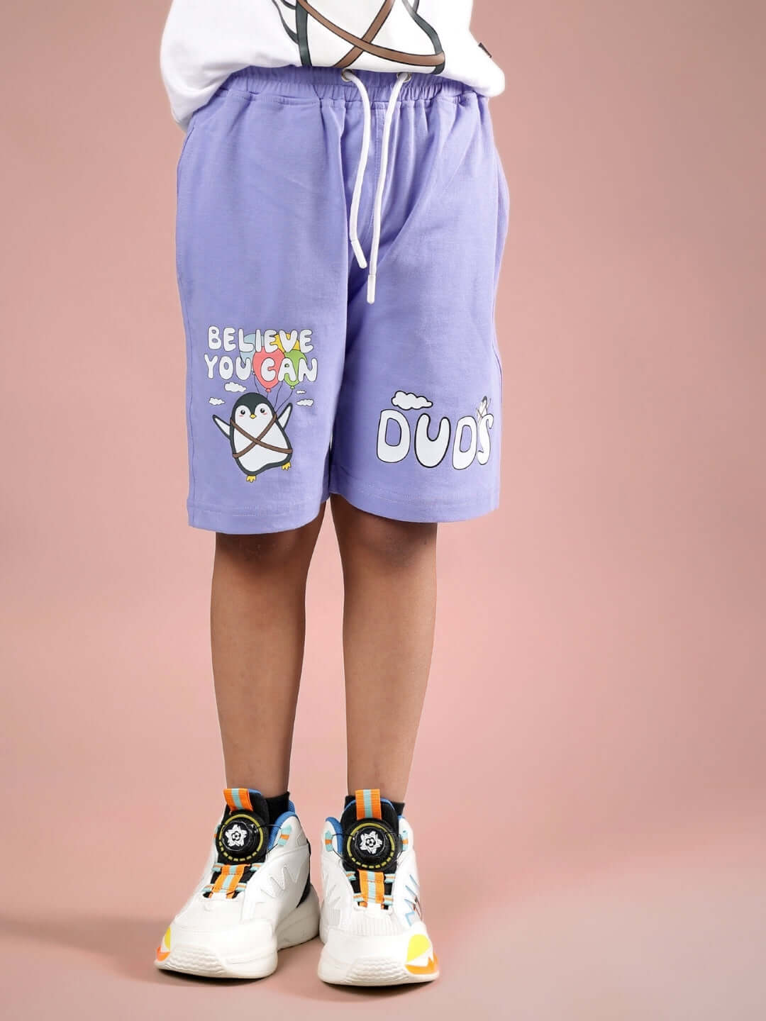 Child wearing lavender BELIEVE shorts by DUDS, featuring motivational print. Customizable size for boys and girls.