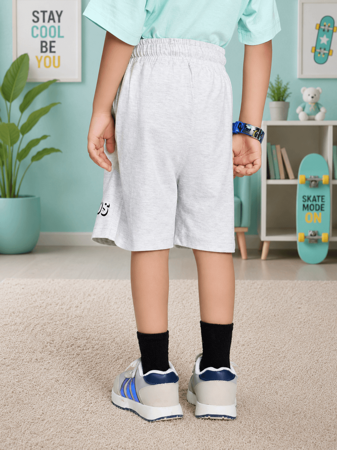 BIRD ON THE KEYS COOL SHORTS FOR BOYS GIRLS LIGHT GRAY worn by a child from the back in a stylish indoor setting.