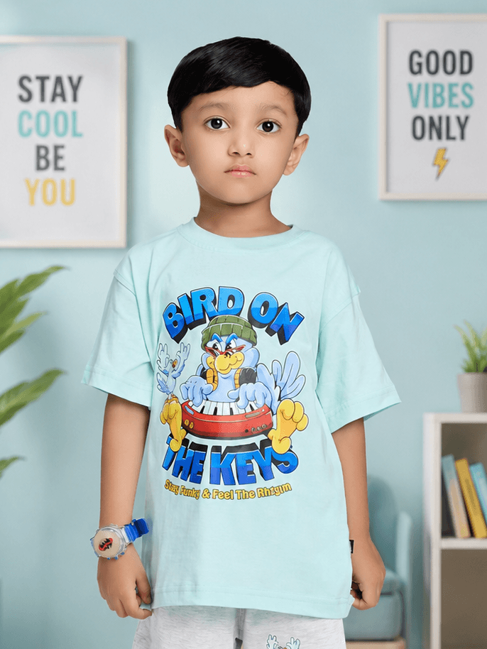 BIRD ON THE KEYS T-SHIRT FOR BOYS GIRLS SKY BLUE worn by a boy, featuring a colorful cartoon design.