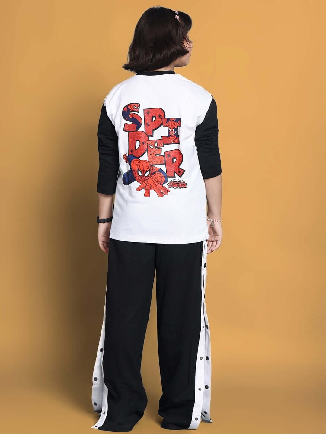 Child wearing a white and black BITSY co-ord set with Spider-Man graphic on the back.