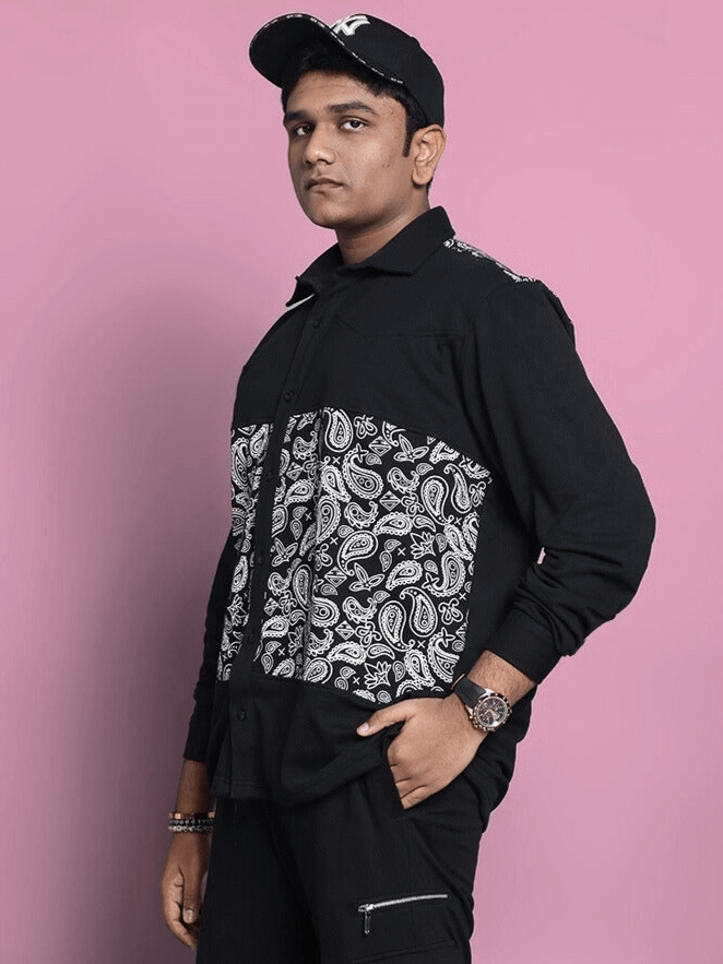 Model wearing COVE SHIRT in black with paisley pattern, tailored by DUDS, available for custom fit orders, on a pink background.