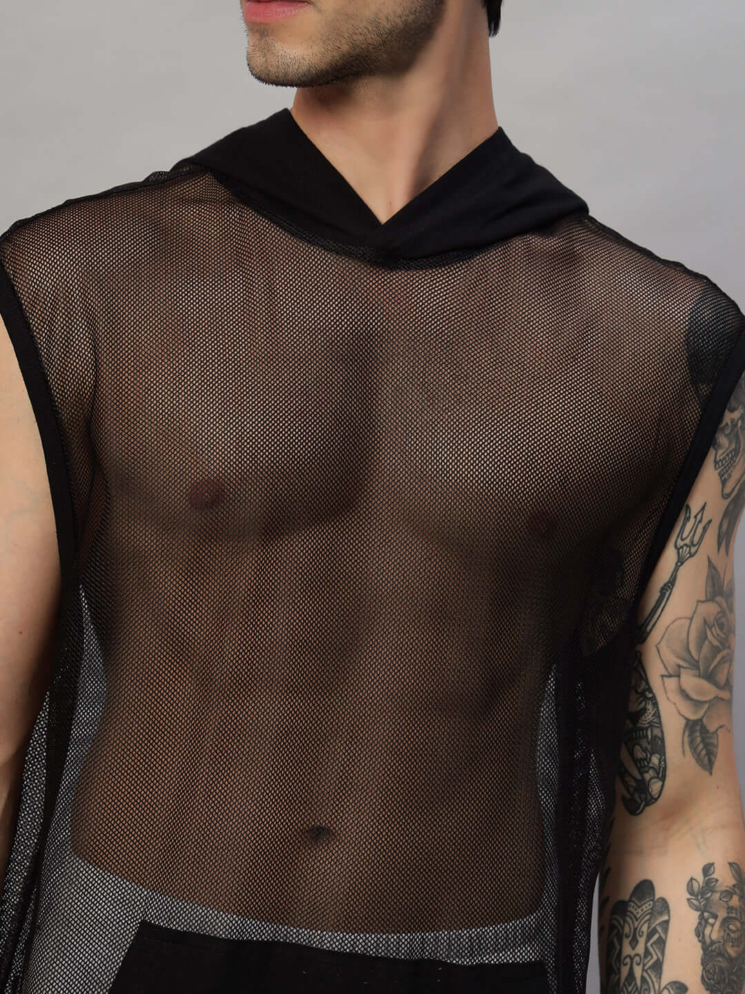 Man wearing a stylish black mesh hooded top showcasing tattooed arm