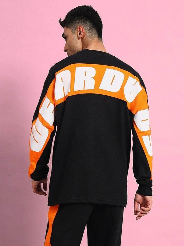 Man wearing Titan Oversized Black Sweatshirt with bold white and orange lettering, made of premium cotton French terry lycra.