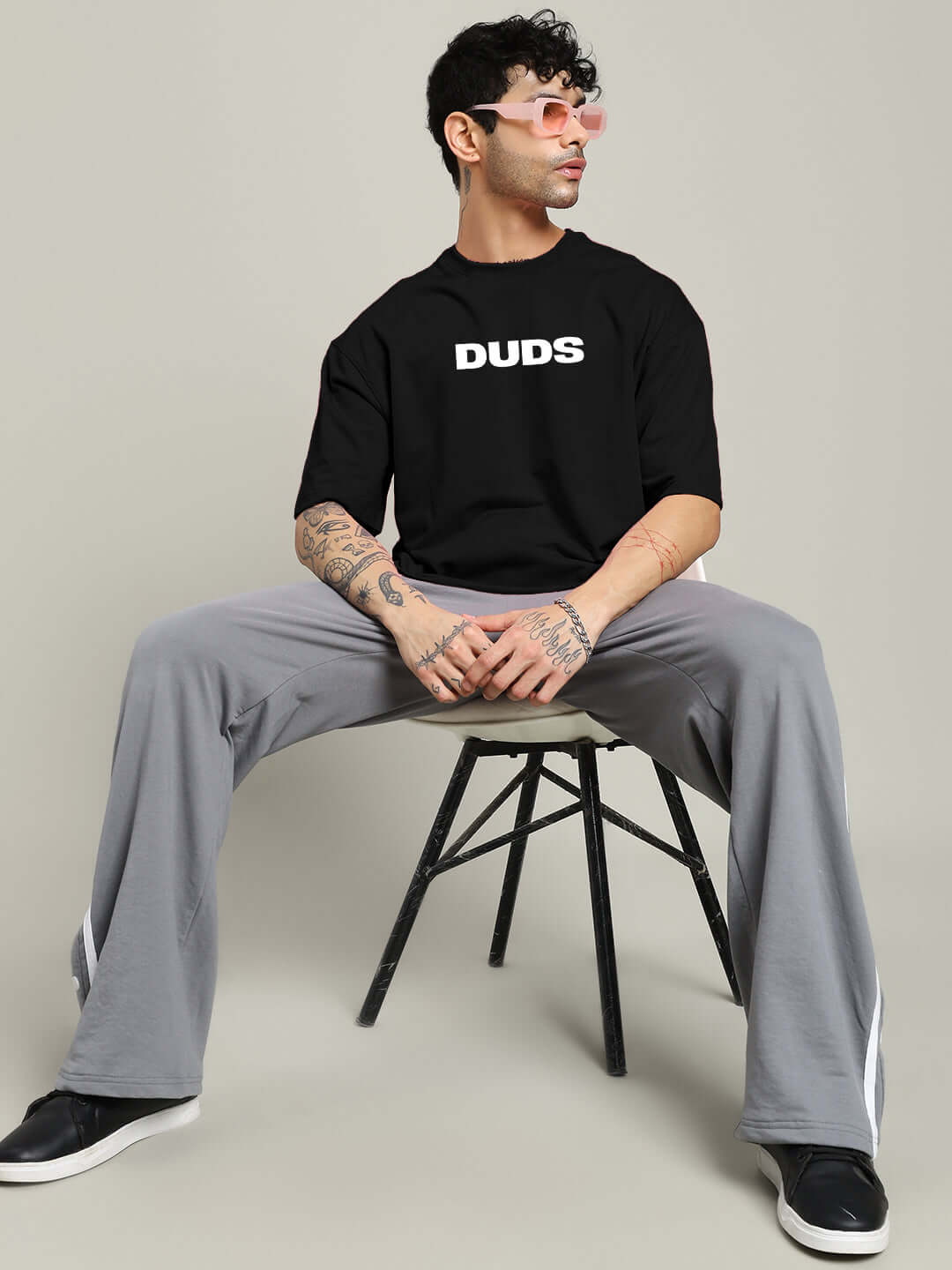 Model wearing the MOTION DROP OVERSIZED T-SHIRT BLACK with graphic, seated in casual streetwear.