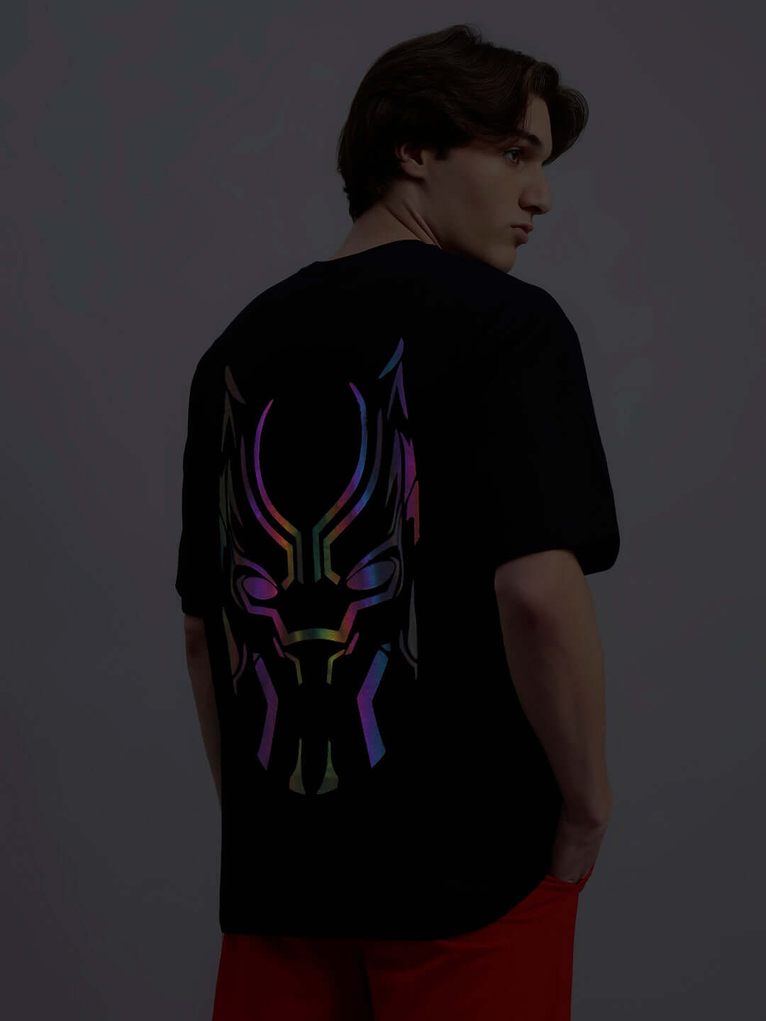 Man wearing a Black Panther reflector oversized t-shirt, showing back design with vibrant reflective graphics, black color.