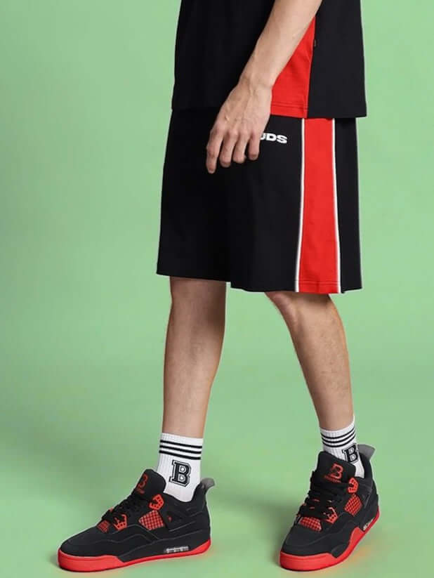 Model wearing DRIFT REGULAR FIT COTTON SHORTS BLACK with red and white stripes, showcasing stylish unisex design for versatile wear.