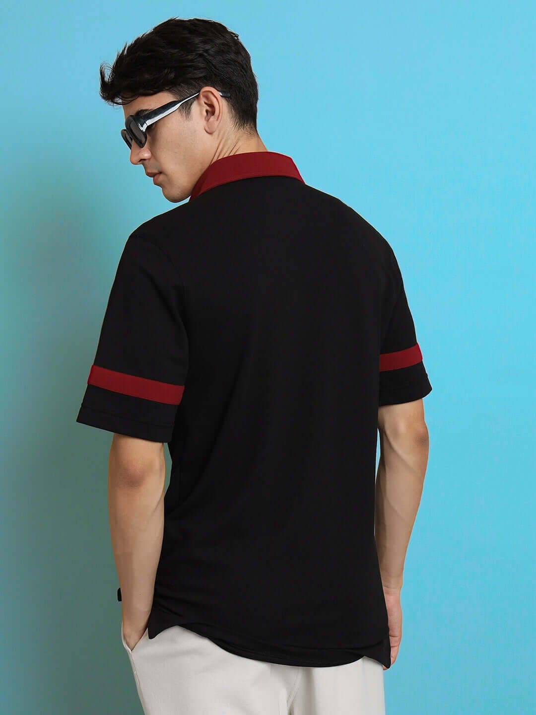 Model wearing a black polo neck t-shirt with red reflective stripes, showcasing half sleeves and a slim fit, against a blue background.