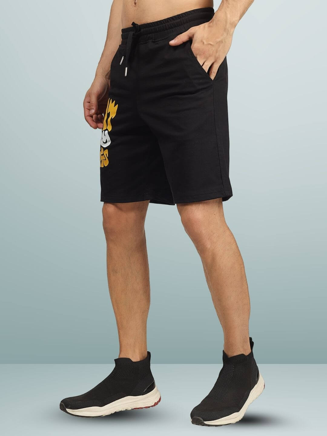 Man wearing EAT MY SHORTS black regular fit shorts with casual sneakers, showcasing side view design and customizable fit options.
