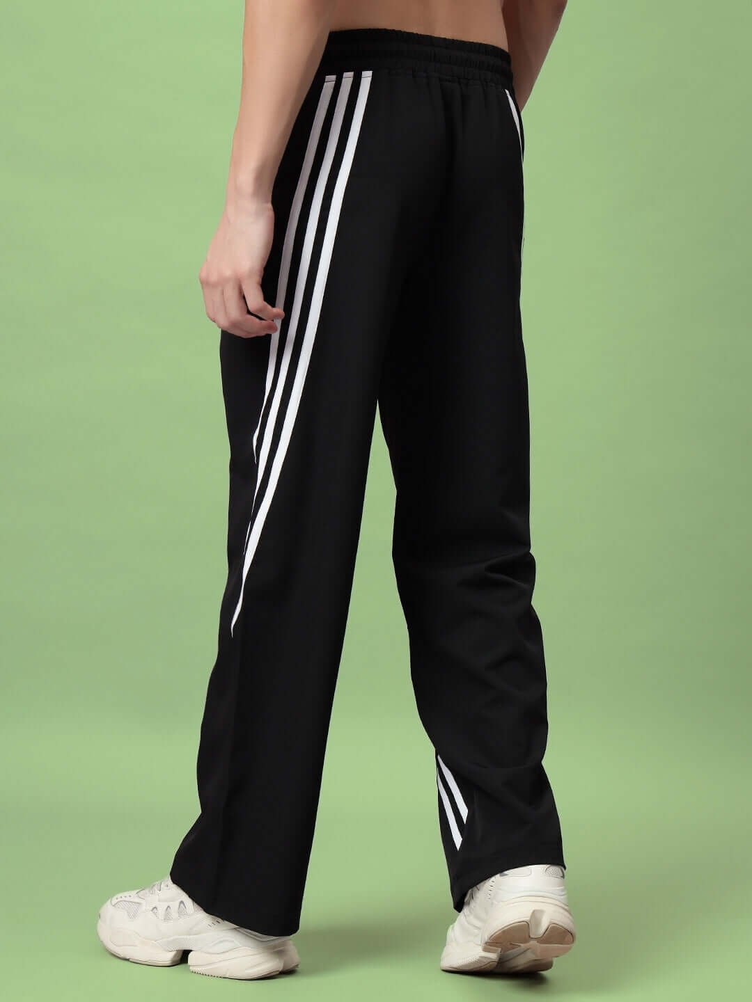 Back view of black cargo pants with white stripes, showcasing relaxed fit and casual style for streetwear fashion.