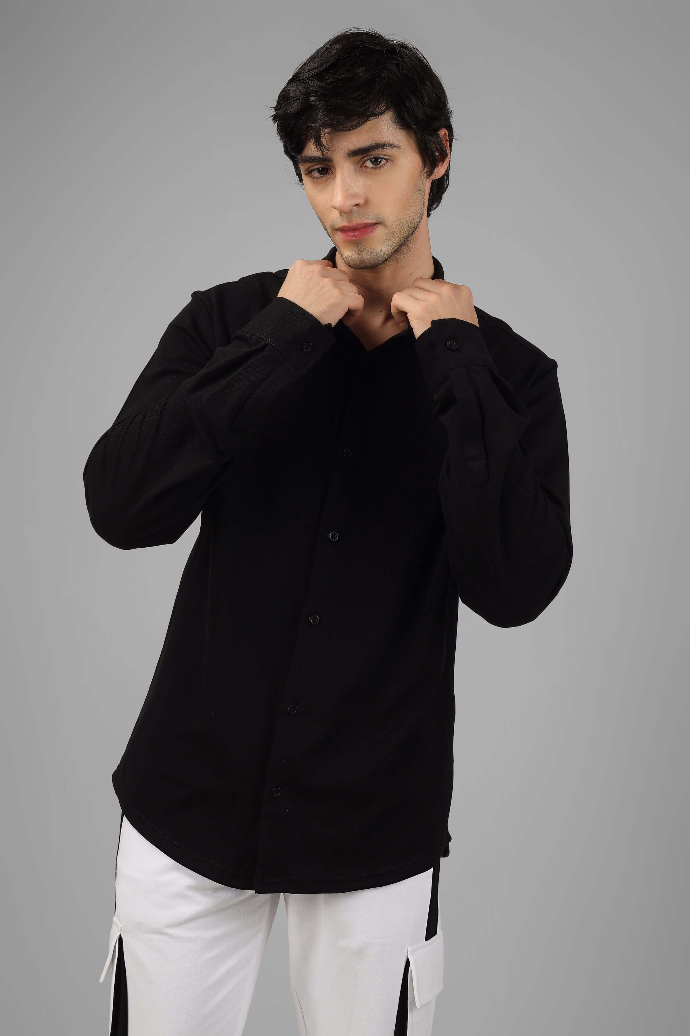 Man wearing a black sporty pique shirt with full sleeves and a curved hem, demonstrating the stretch and comfort of the fabric.