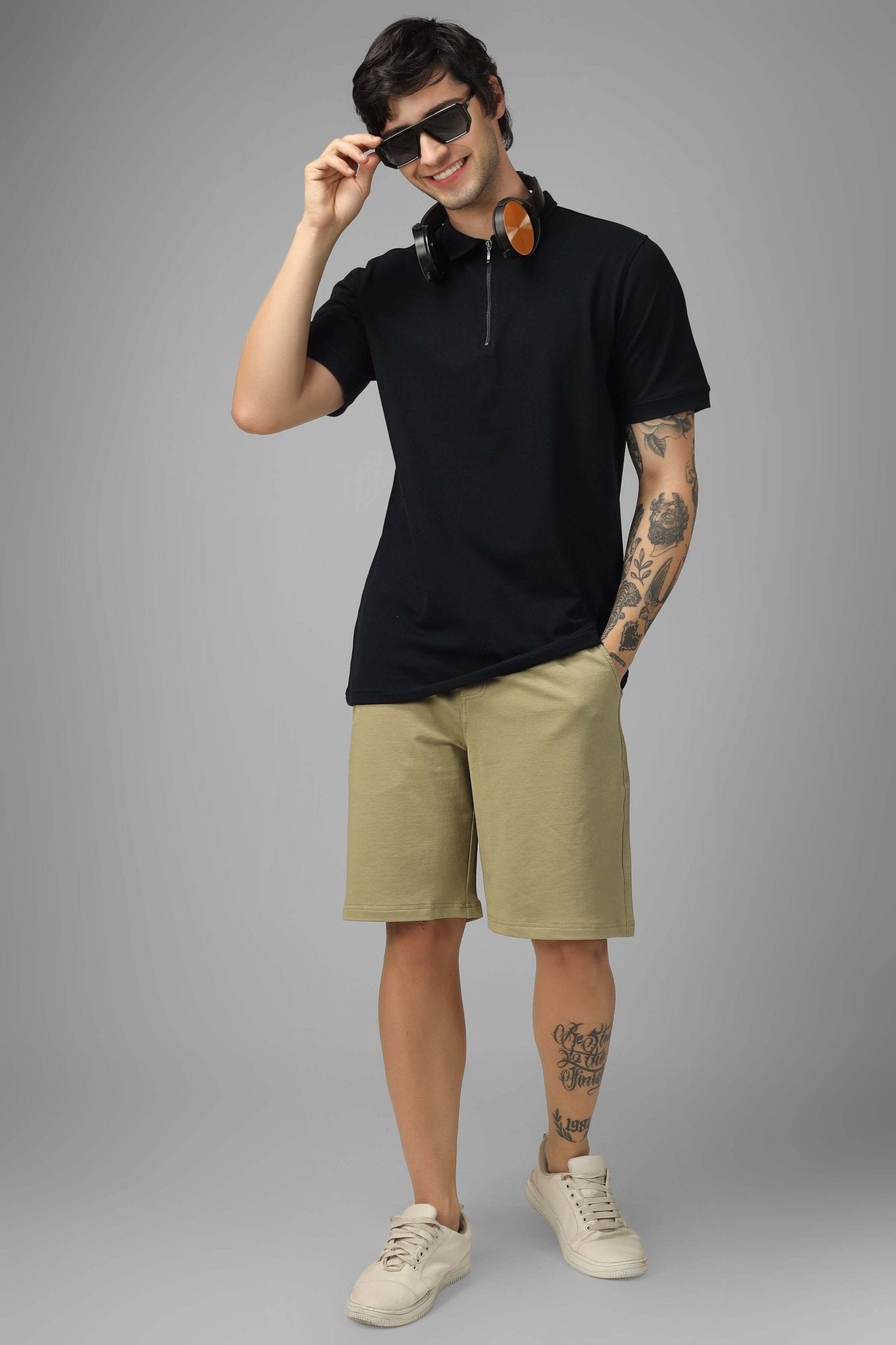 Model wearing ZIPPER POLO NECK ZIPPER T-SHIRT BLACK with beige shorts and sunglasses, featuring double zipper detailing and structured collar.