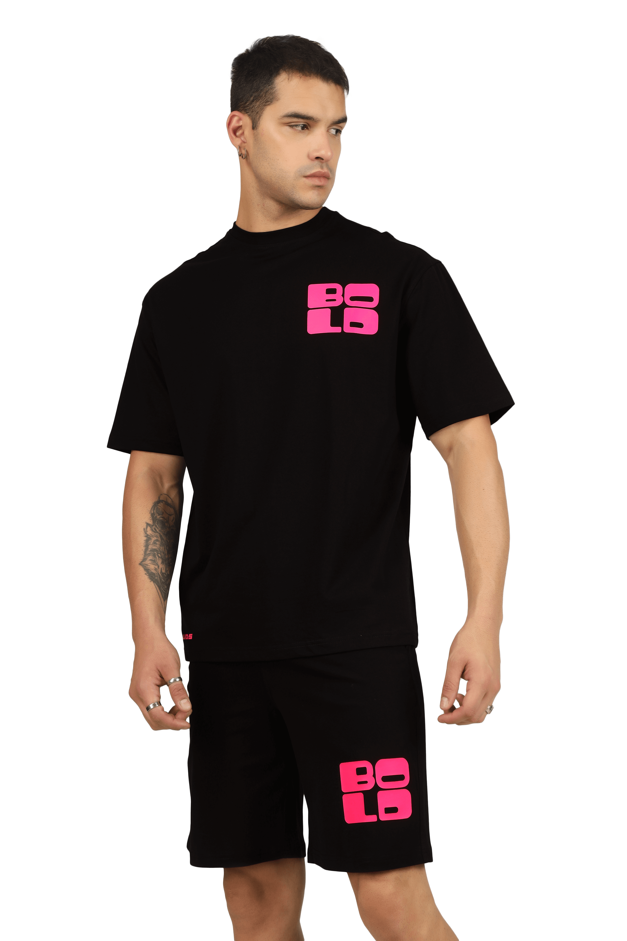 Model wearing black CO-ORD set with bold pink print, short sleeves and matching shorts, showcasing modern fashion style.