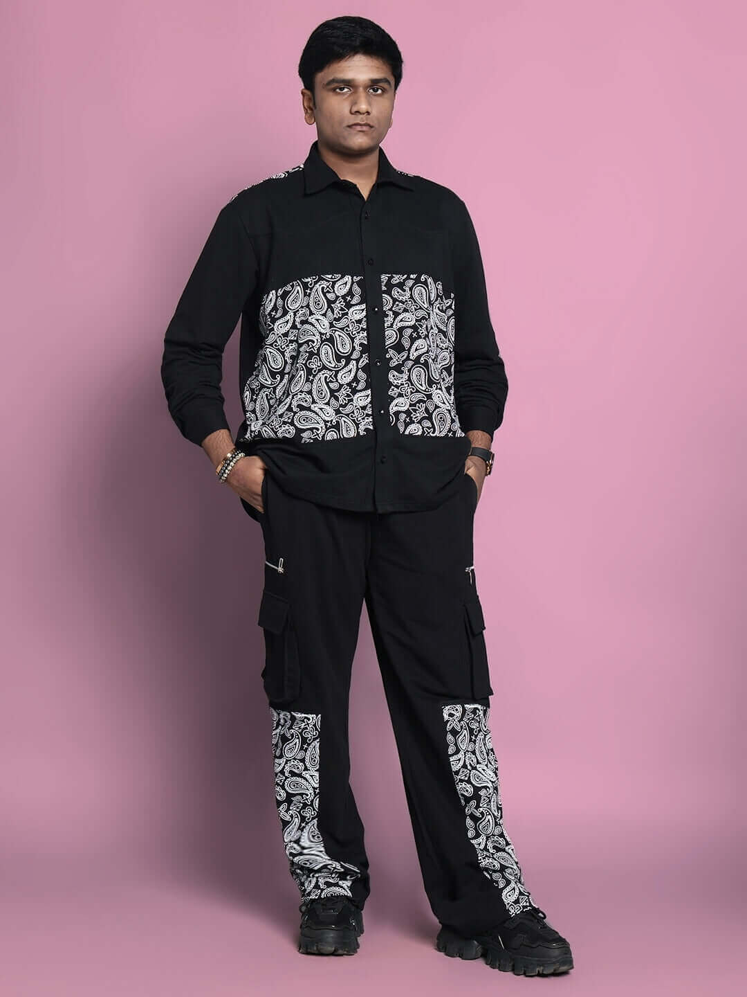 Man modeling COVE CO-ORD SET in black premium cotton fabric with paisley design, standing against a pink background.