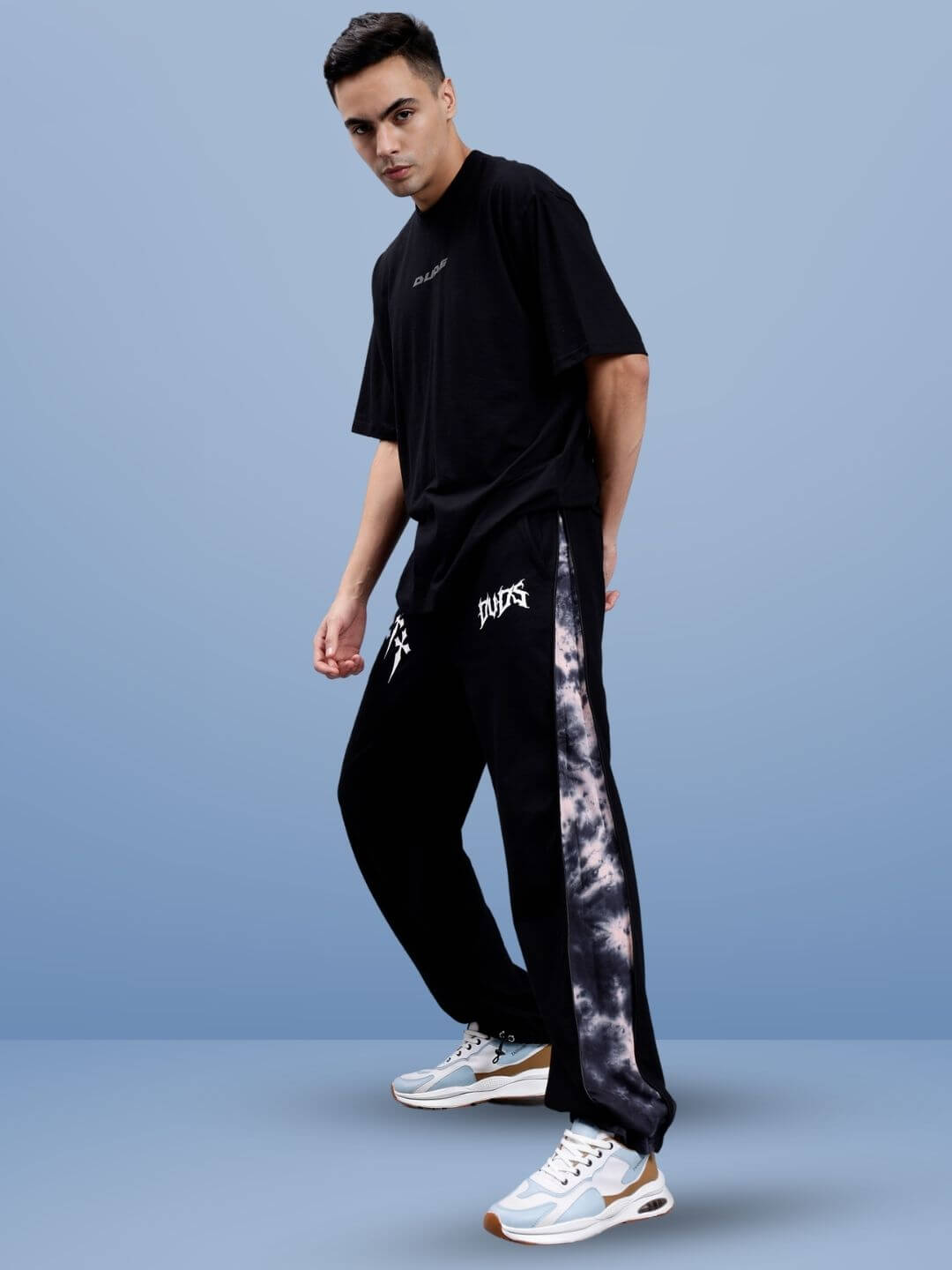 Model wearing black T-shirt with DUDS joggers featuring a tie-dye panel, showcasing casual streetwear style.