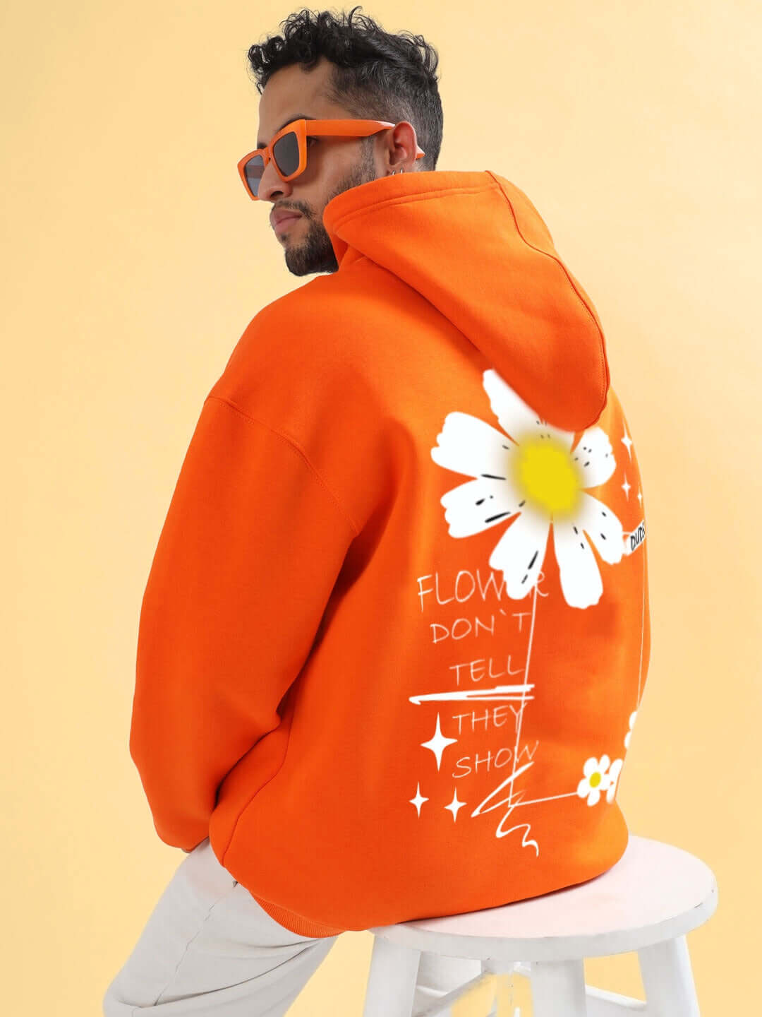 Man wearing BLOOM QUOTE FLEECE OVERSIZED HOODIE ORANGE with floral graphic, showcasing relaxed fit and vibrant orange color.