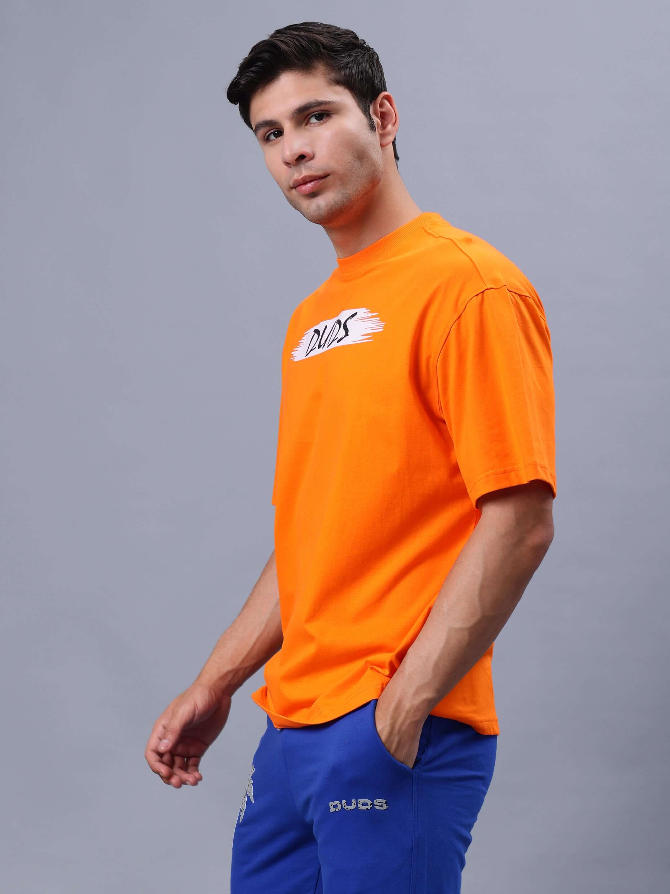 Model wearing orange BLOOM QUOTE over-sized t-shirt from DUDS, showcasing casual fashion style.