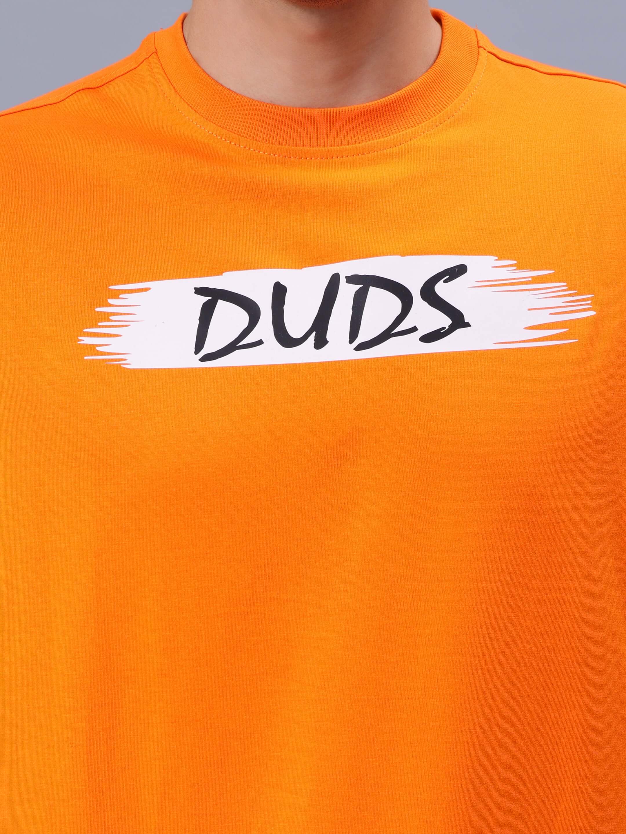 Person wearing orange over-sized T-shirt with DUDS logo, showcasing customizable handmade apparel option.