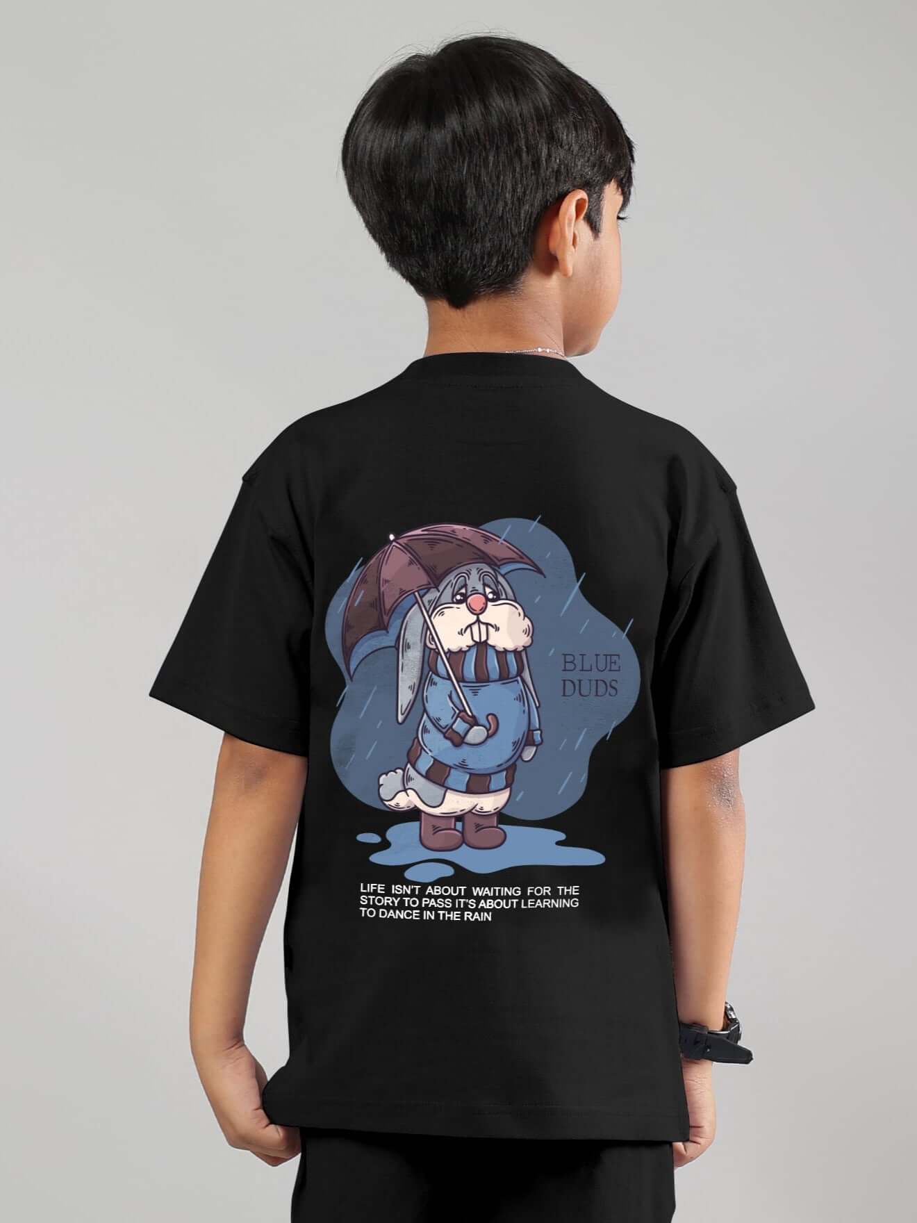 Child wearing a black Blue Lapin T-shirt with a bunny print and umbrella design on the back.
