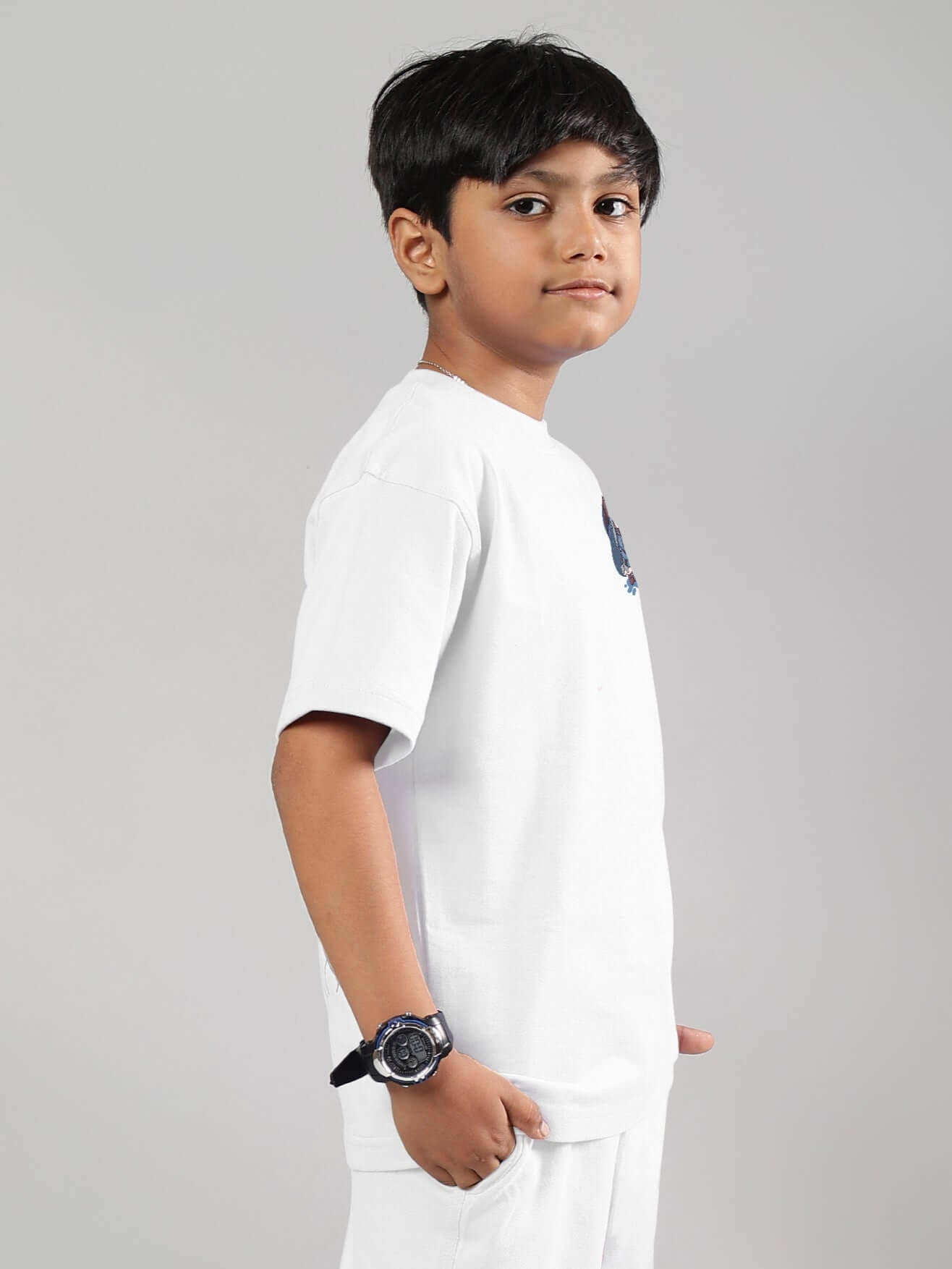 Child wearing white Blue Lapin T-shirt from DUDS, side view with hand in pocket, showcases casual and customizable fashion for boys and girls.