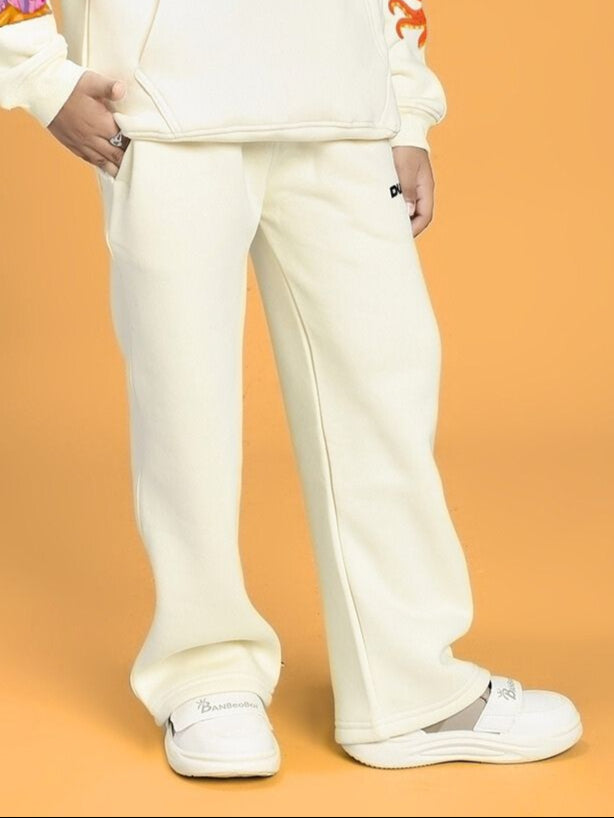Child wearing BLUE OCEAN WORLD FLEECE JOGGER FOR BOYS AND GIRLS OFF-WHITE, standing against an orange background with matching shoes.