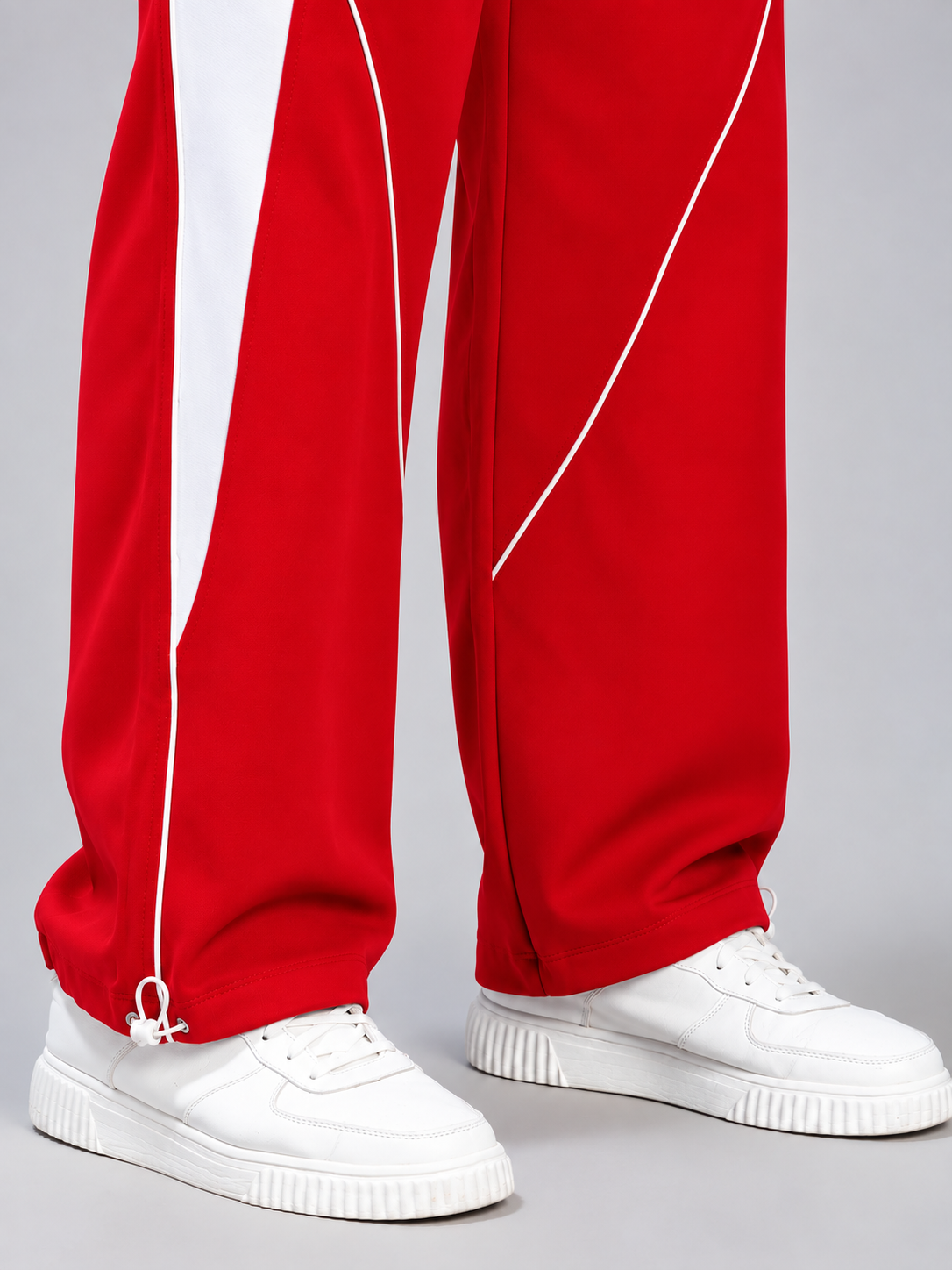 BOLD ELECTRIC RELAXED FIT JOGGERS RED WHITE styled with white sneakers, close-up view of ankle zipper detail