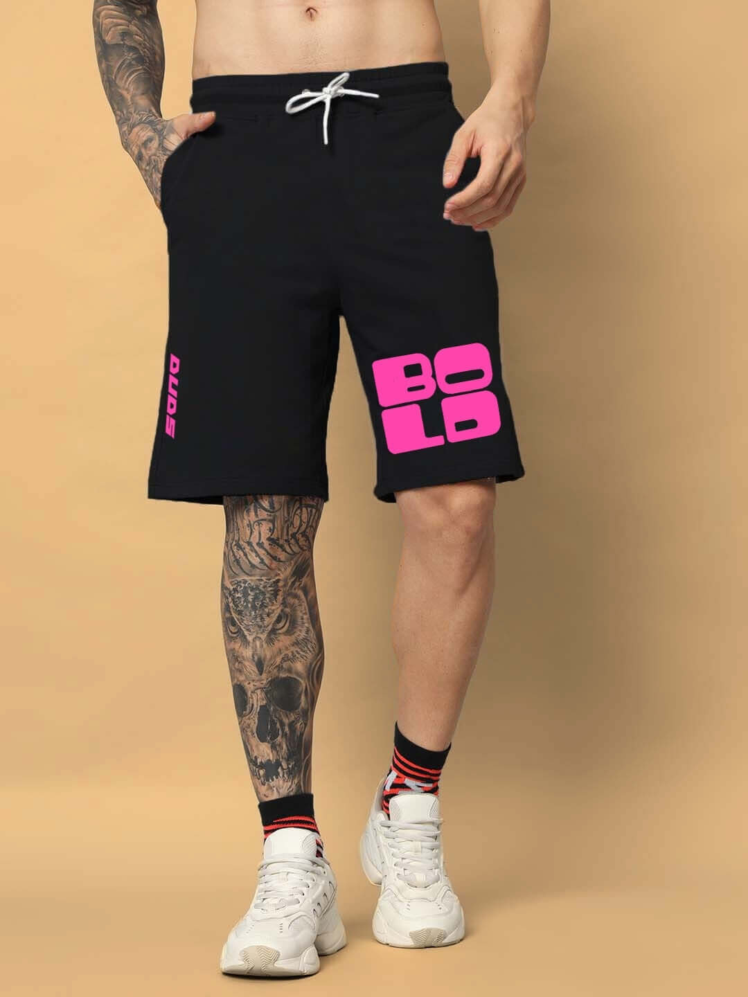 Man wearing black BOLD regular fit shorts with pink lettering, showcasing casual athletic style and custom fit options.