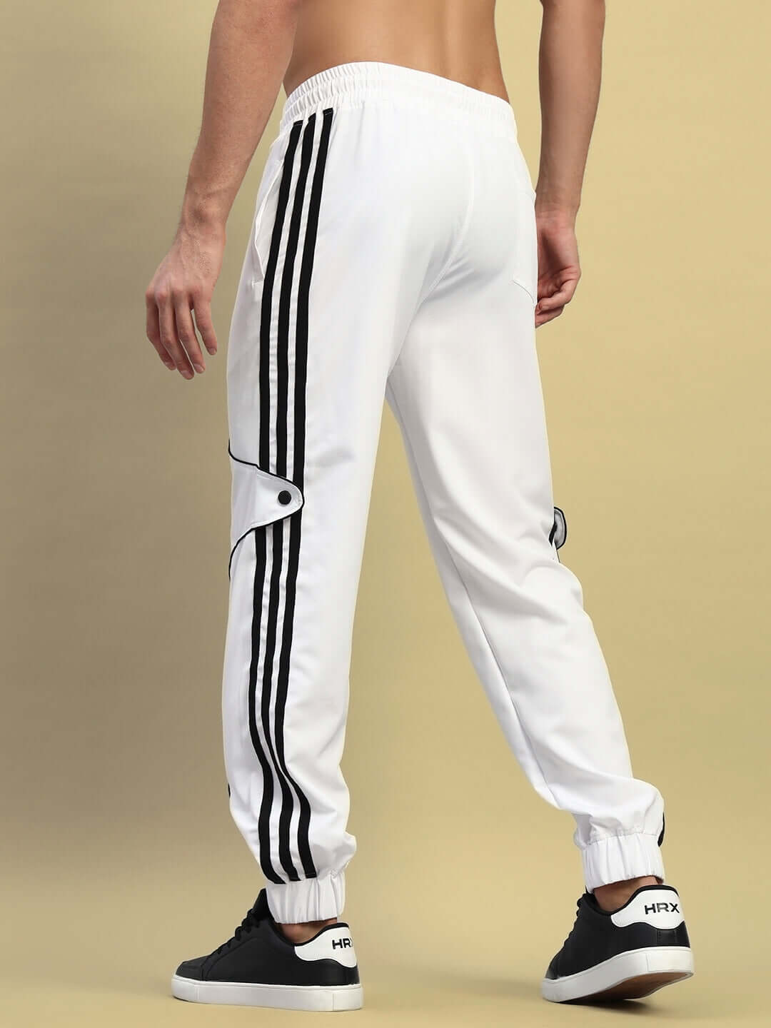 Model wearing white Bolson Stripes relaxed-fit joggers with side stripes and black sneakers, display of sporty casual wear.