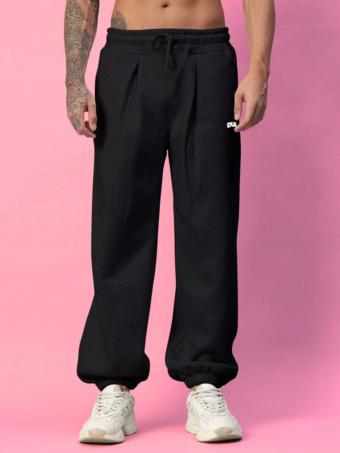 BONA-FIDE Cotton Fleece Pant in Black, featuring an elastic waistband, worn by a model standing against a pink background with white sneakers.