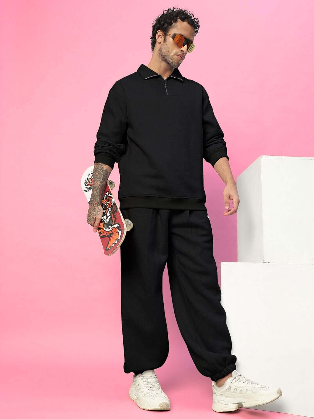 Model wearing Bona-Fide Cotton Fleece Pant in black, holding a skateboard, against a pink background.