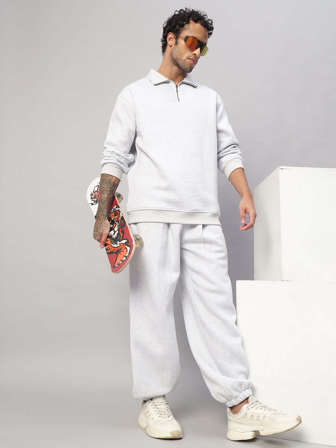 Man wearing BONAFIDE FLEECE CO-ORD MELANGE GREY set, holding a skateboard, showcasing casual and stylish loungewear.