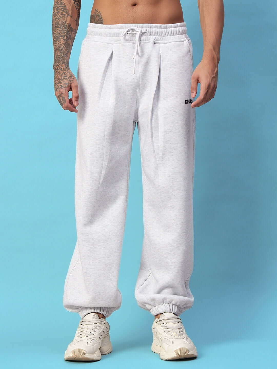 Person wearing Bona-Fide fleece pant in melange grey, showcasing comfort and style against a blue background.