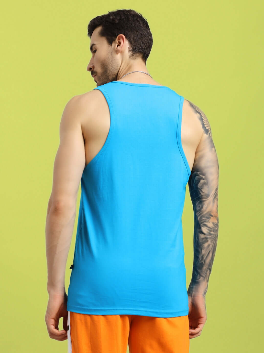 Back view of model wearing bright blue BONNY GYM T-shirt, showcasing sleek design against a green background.