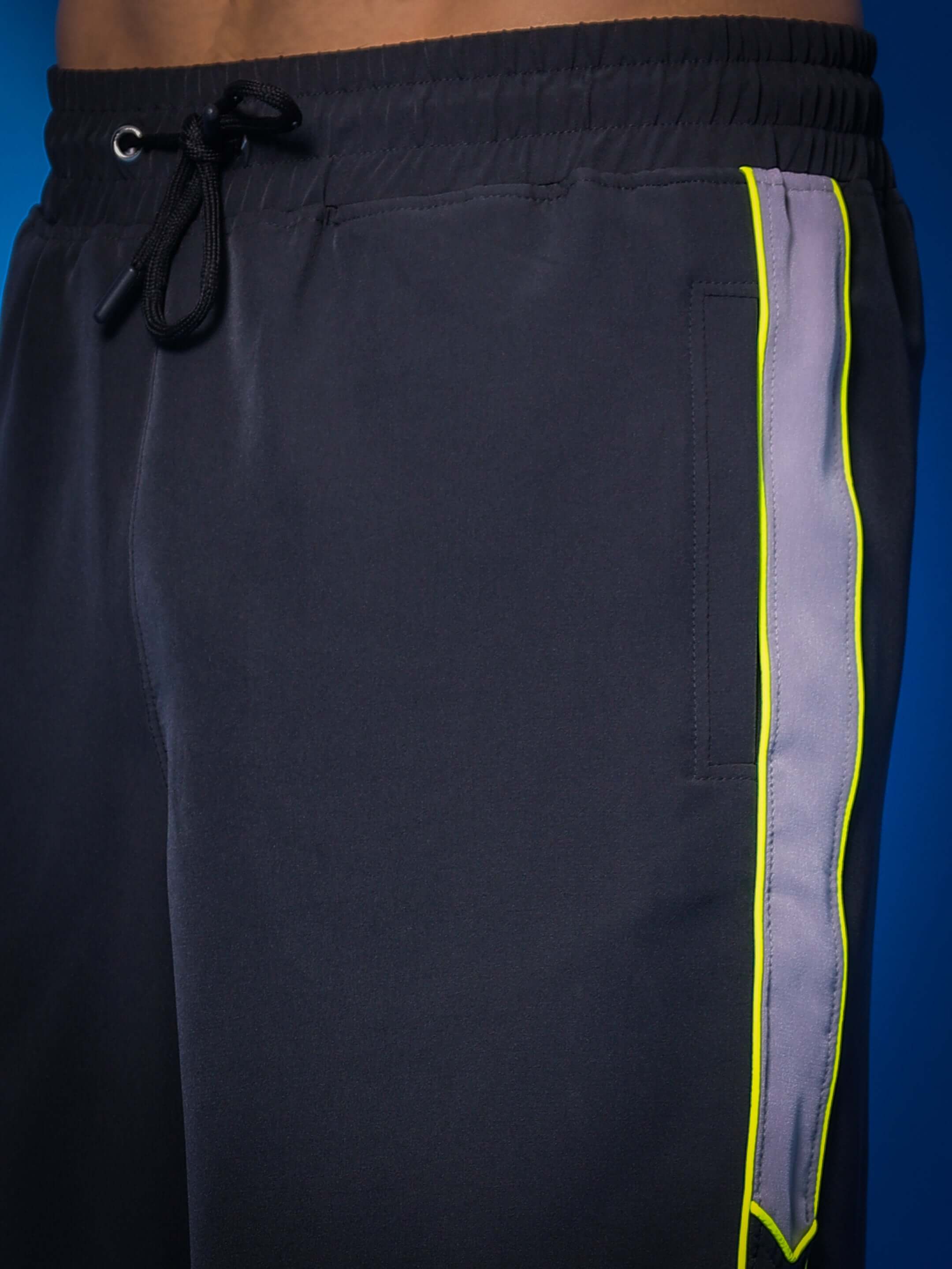 Close-up of Boomer Shorts in dark grey with neon green piping, featuring adjustable drawstring and stylish design.