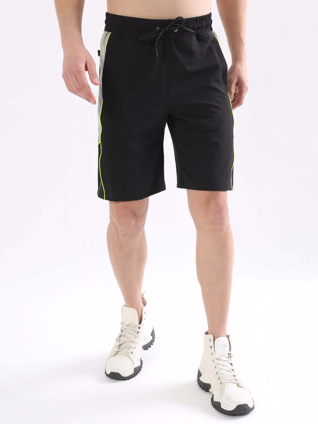 Model wearing black BOOMER shorts with neon green piping, showcasing custom fit option for personalized sizing.
