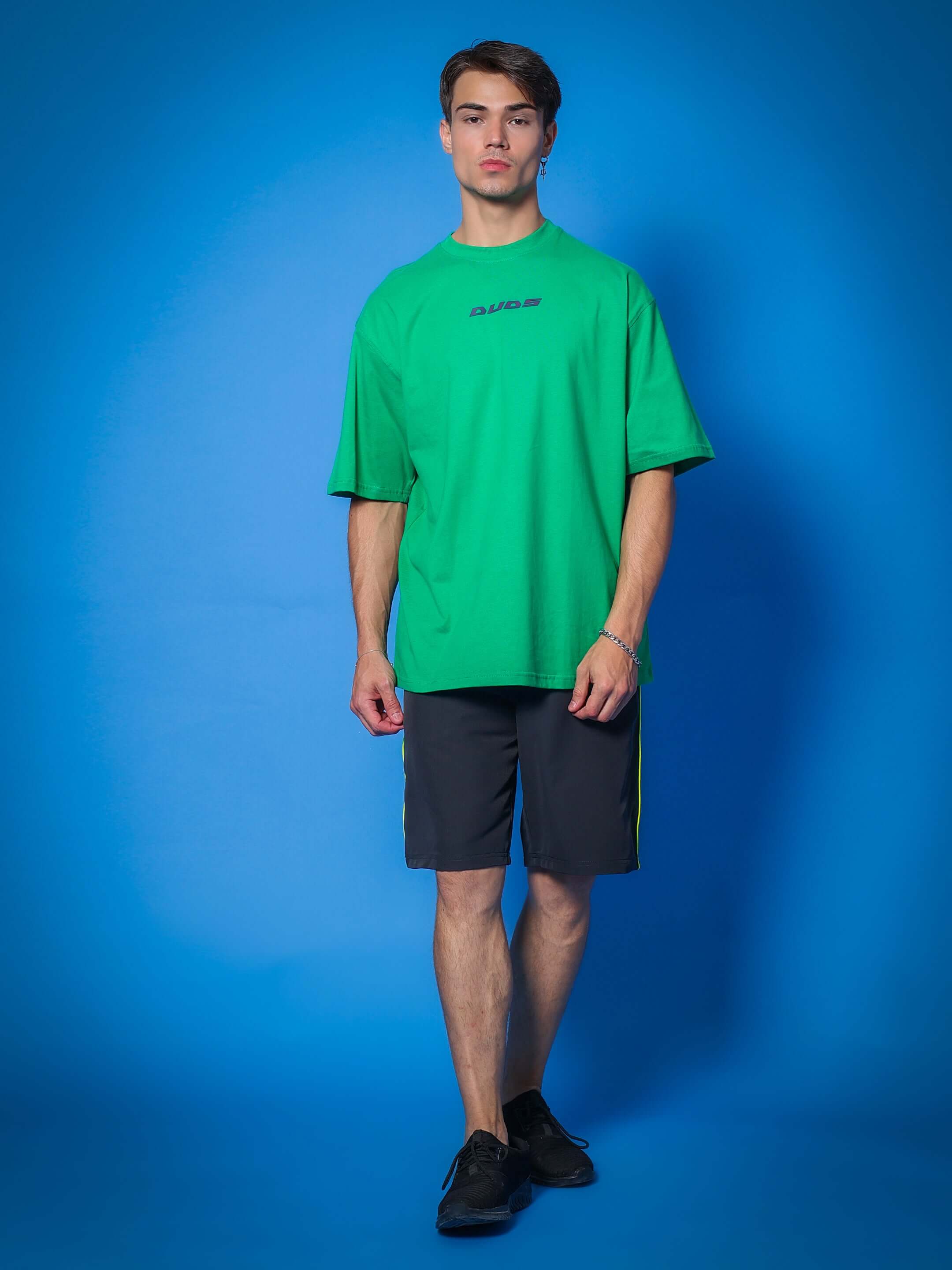 Model wearing Boomer Shorts in dark grey with neon green piping, paired with a green t-shirt, showcasing a trendy casual look.