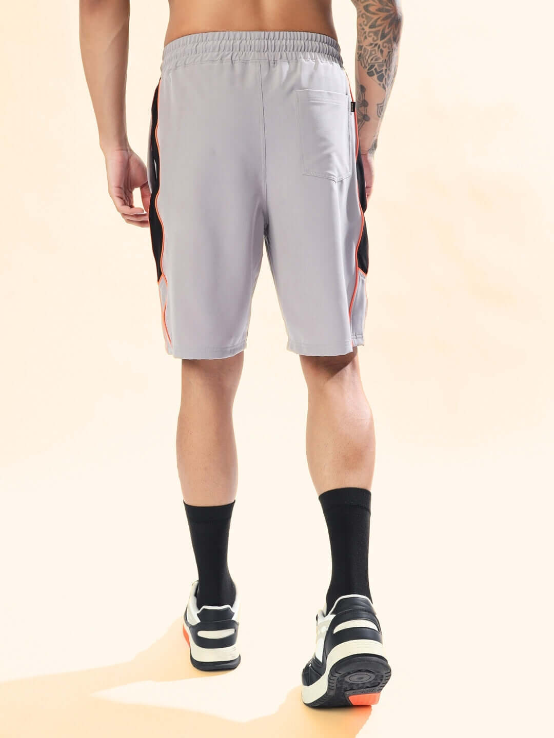 Back view of BOOMER SHORTS GREY WITH ORANGE PIPING worn by a person.