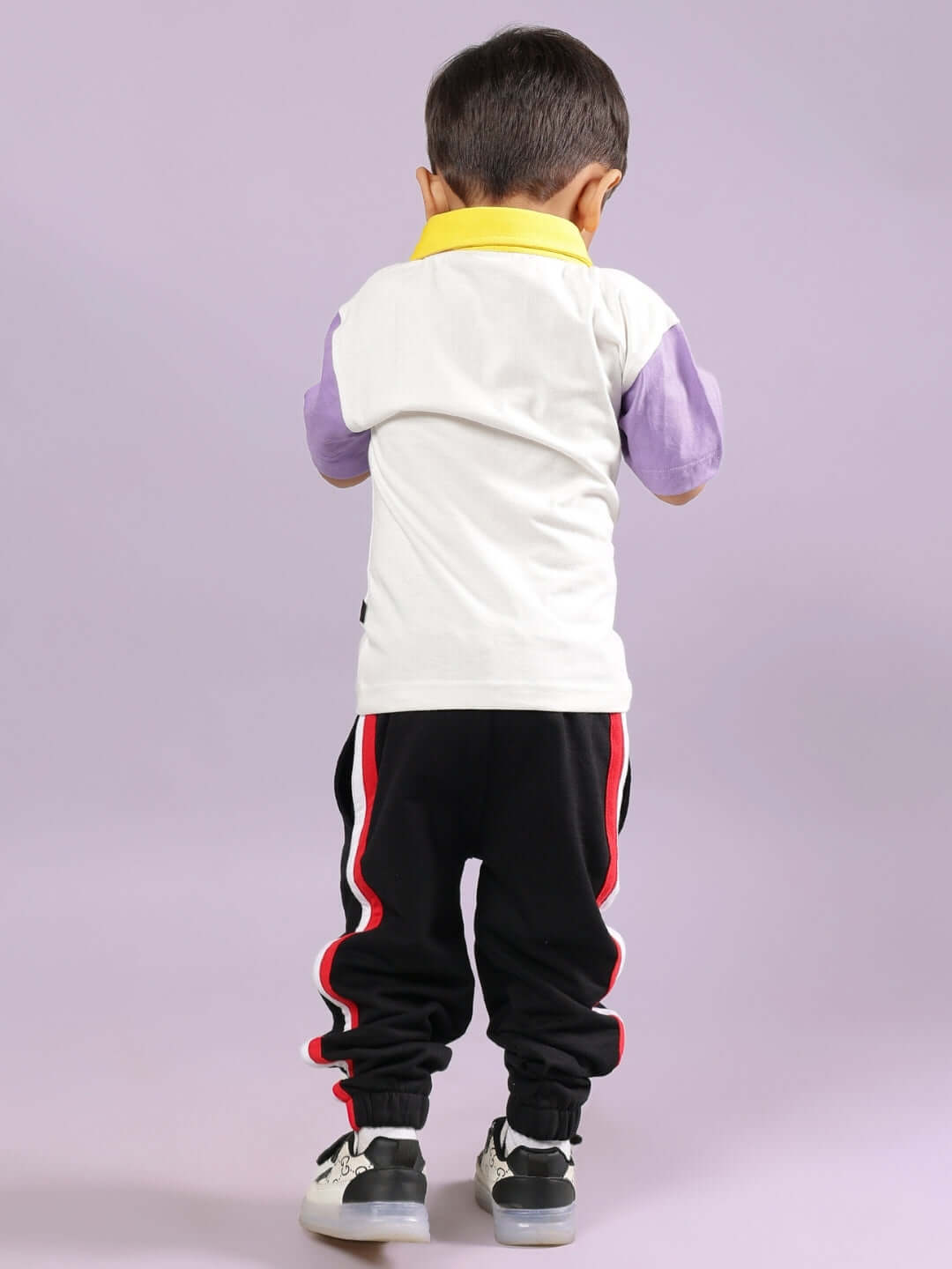 Child wearing BORNEO CO-ORD FOR BOYS & GIRLS OFF WHITE-BLACK outfit, featuring a white shirt and black pants with red stripes, facing away.