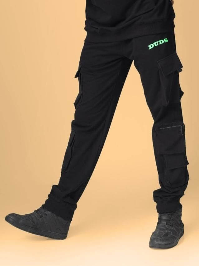 Person wearing black box pocket cargo jogger pants by DUDS, featuring multiple pockets and logo, designed for custom fit and made to order.
