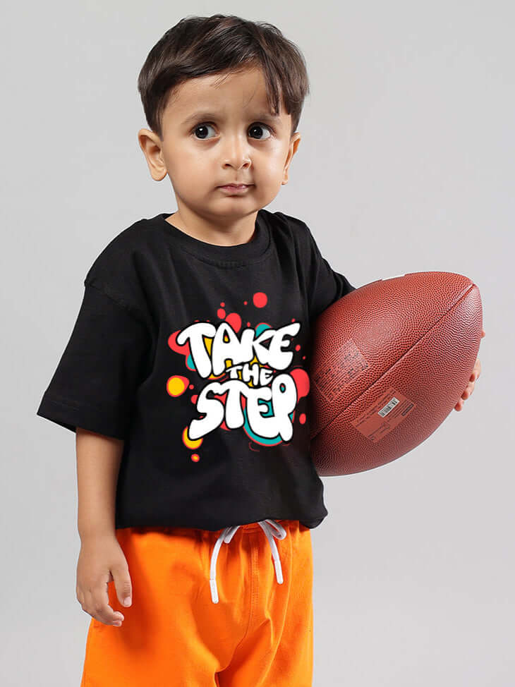 Child wearing a black 'Take the Step' t-shirt, holding a football.