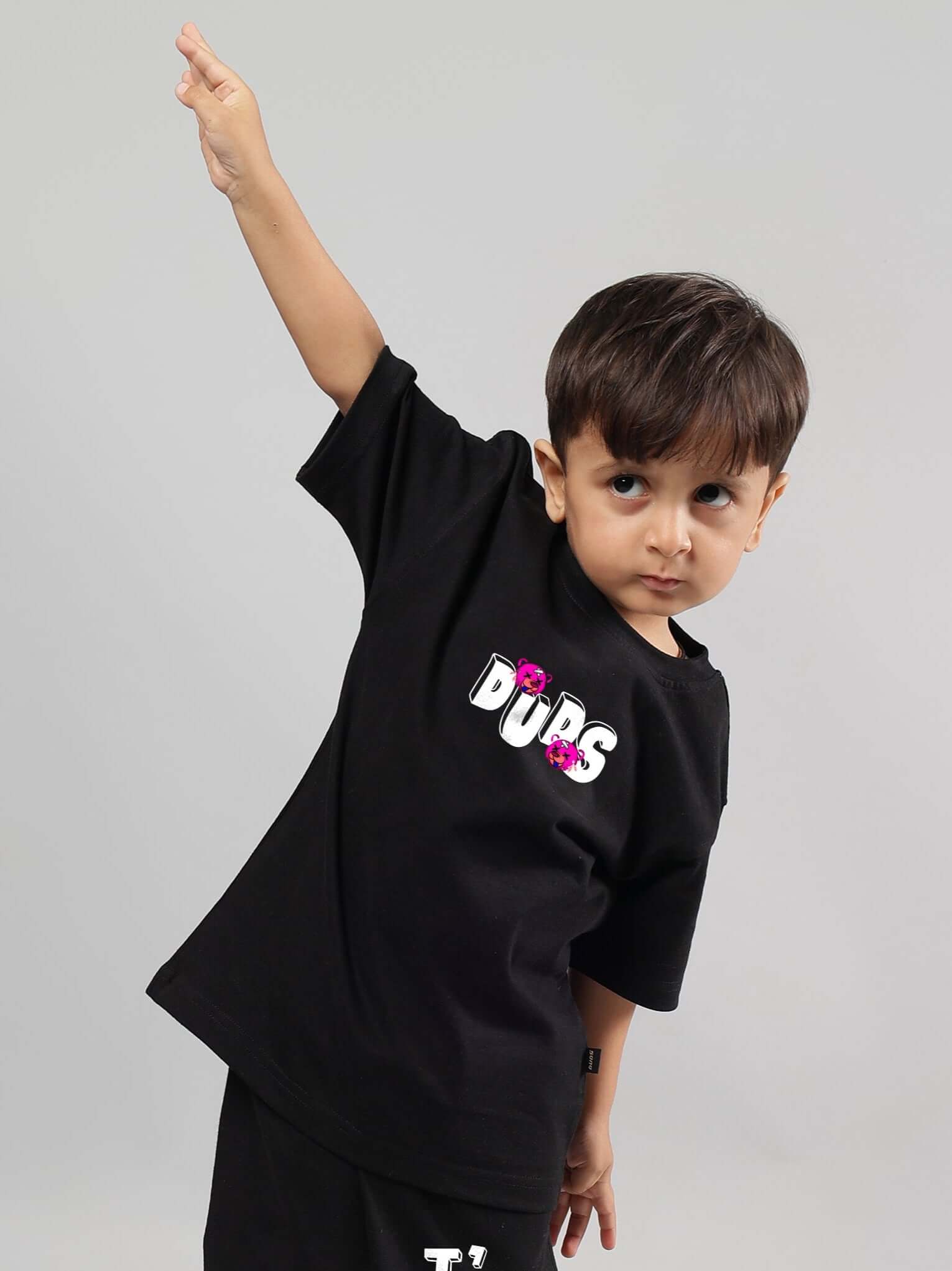Young child wearing I'M OK black T-shirt by DUDS, posing with arm raised, showcasing custom fashion for boys and girls.