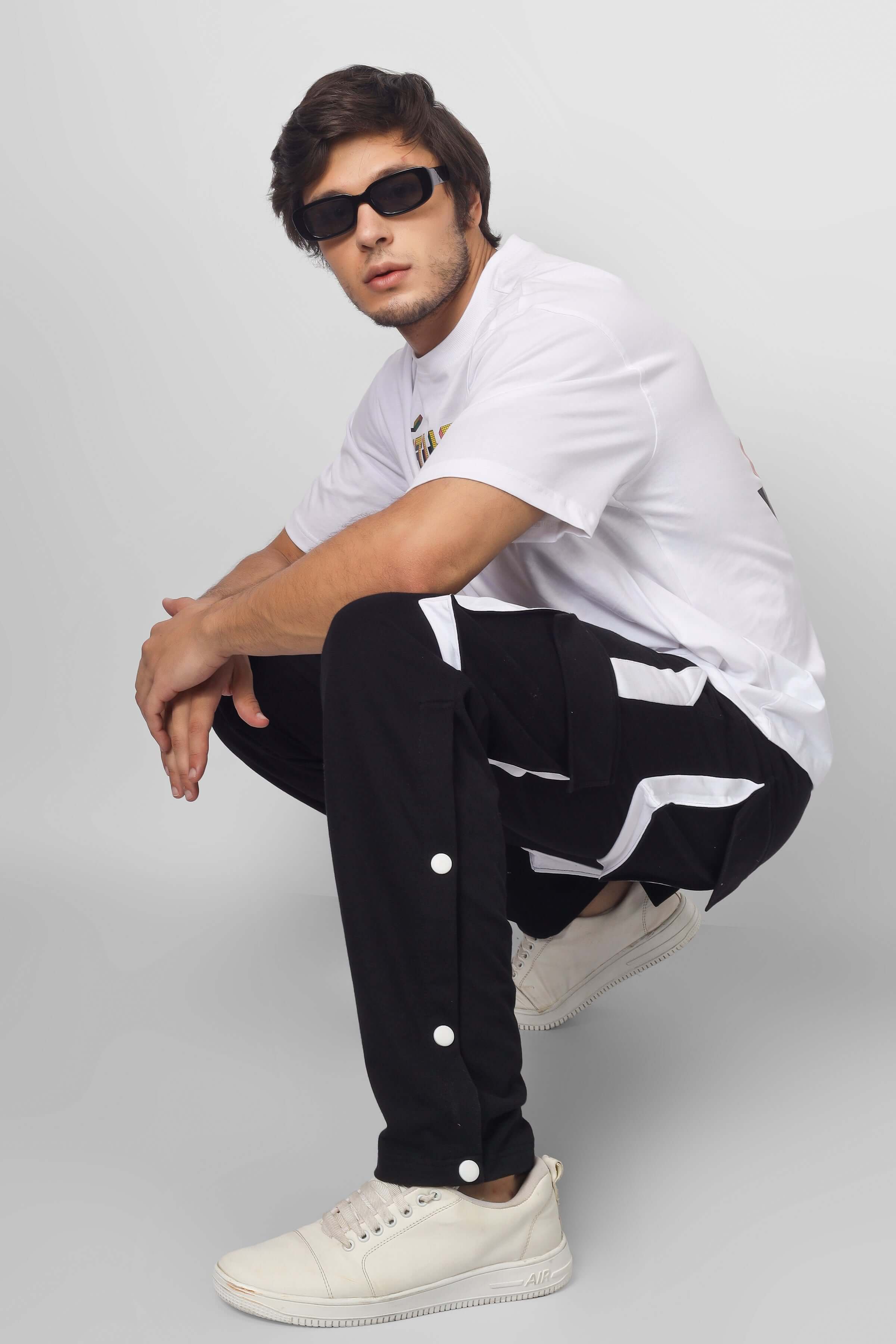 Model wearing BRACKET CARGO PANT in black & white highlights, featuring custom fit option, by DUDS, with sneakers and sunglasses.