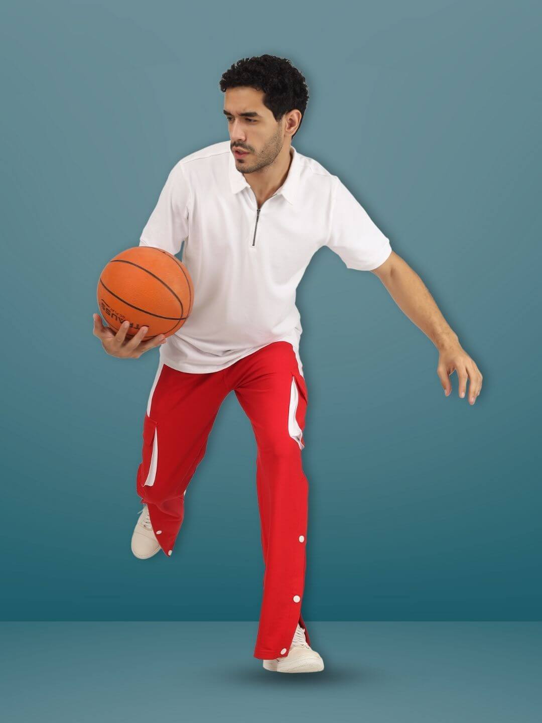 Model wearing BRACKET CARGO PANT in red and white, styled for active wear, holding a basketball, highlighting sporty design and fit.