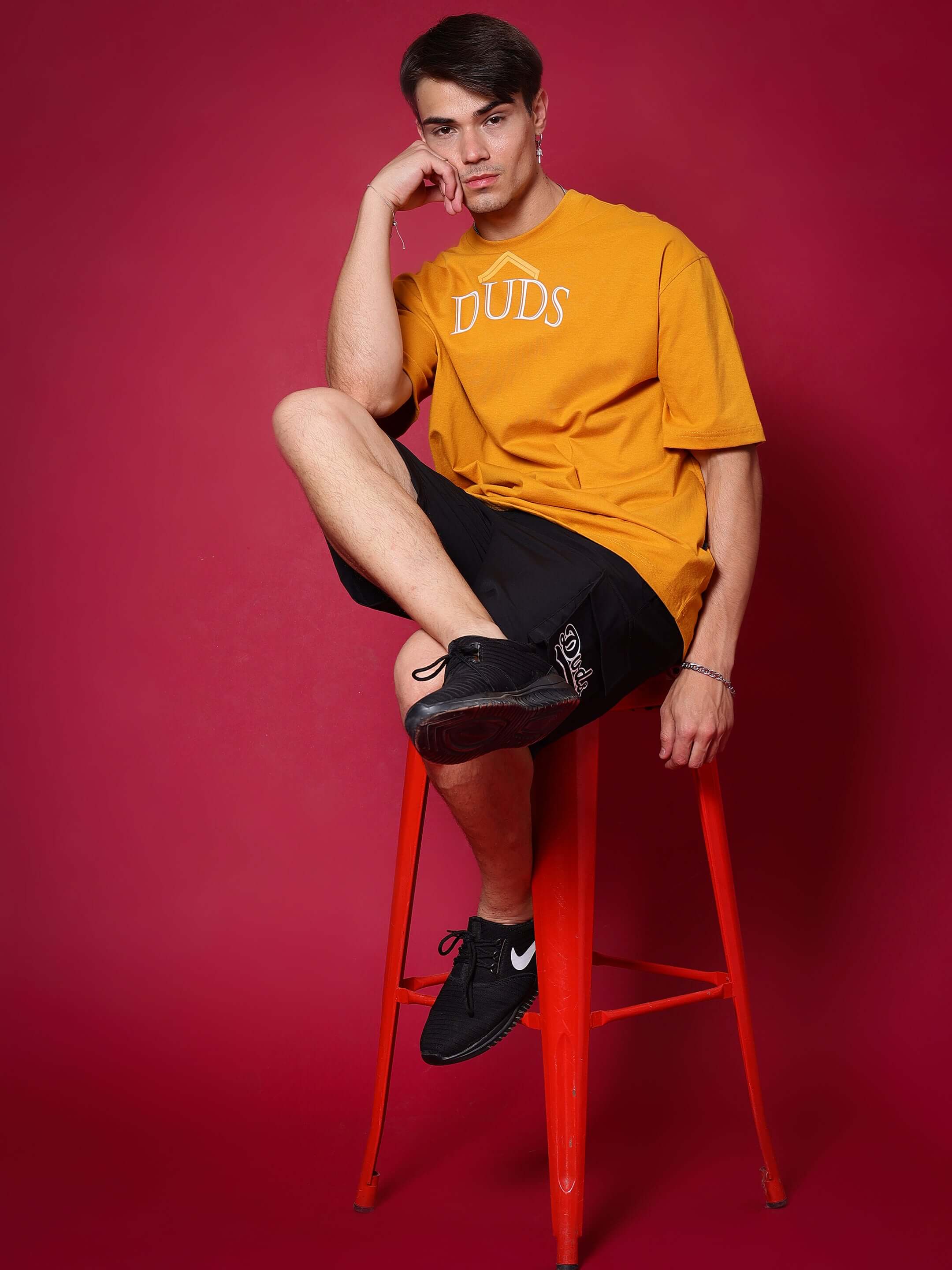 Person wearing Brawny black cargo shorts and orange DUDS shirt sitting on a red stool.