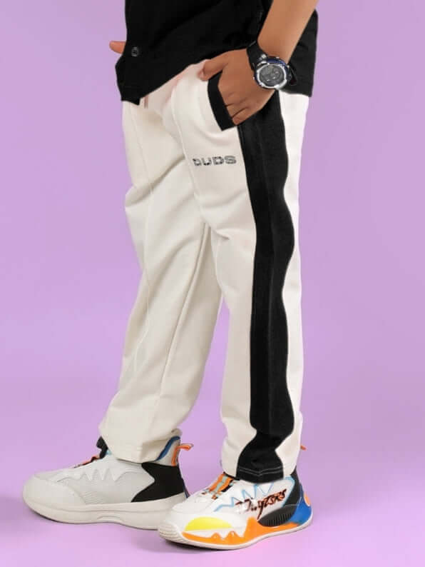 Child wearing off-white and black Breezer Jogger by DUDS on a purple background, showcasing comfort and style for boys and girls.