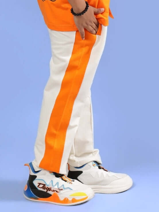 Children's off-white joggers with orange stripe, designed for boys and girls. Unique custom fit option available. Fashionable kidswear.