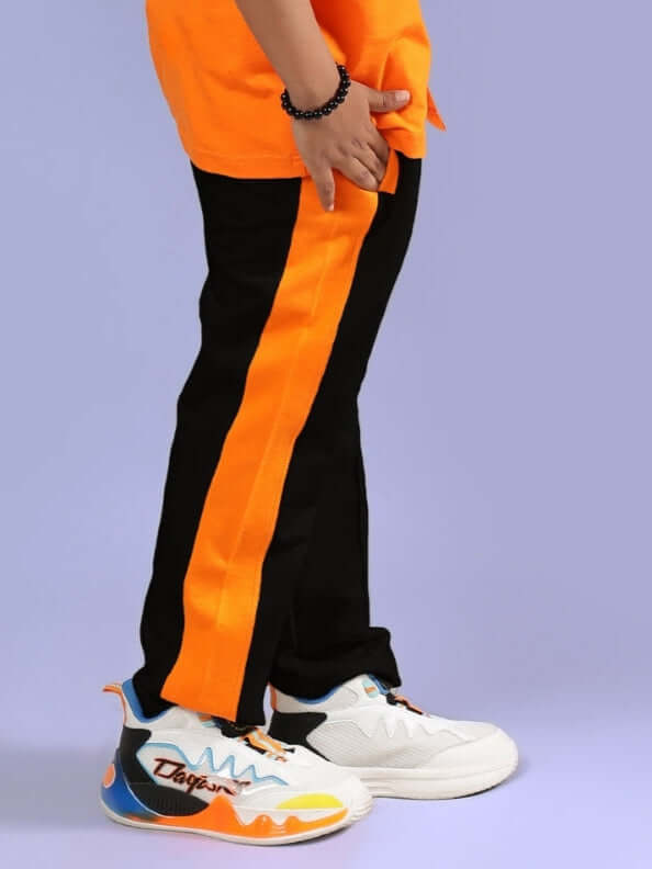 A child wearing BREEZER Jogger in black and orange with custom-fit options, designed for boys and girls by DUDS, shown with colorful sneakers.