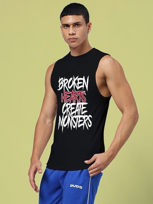 Man wearing BROKEN HEART PRINT SLEEVELESS T-SHIRT BLACK with unique design and graphic text on front, casual and trendy style.