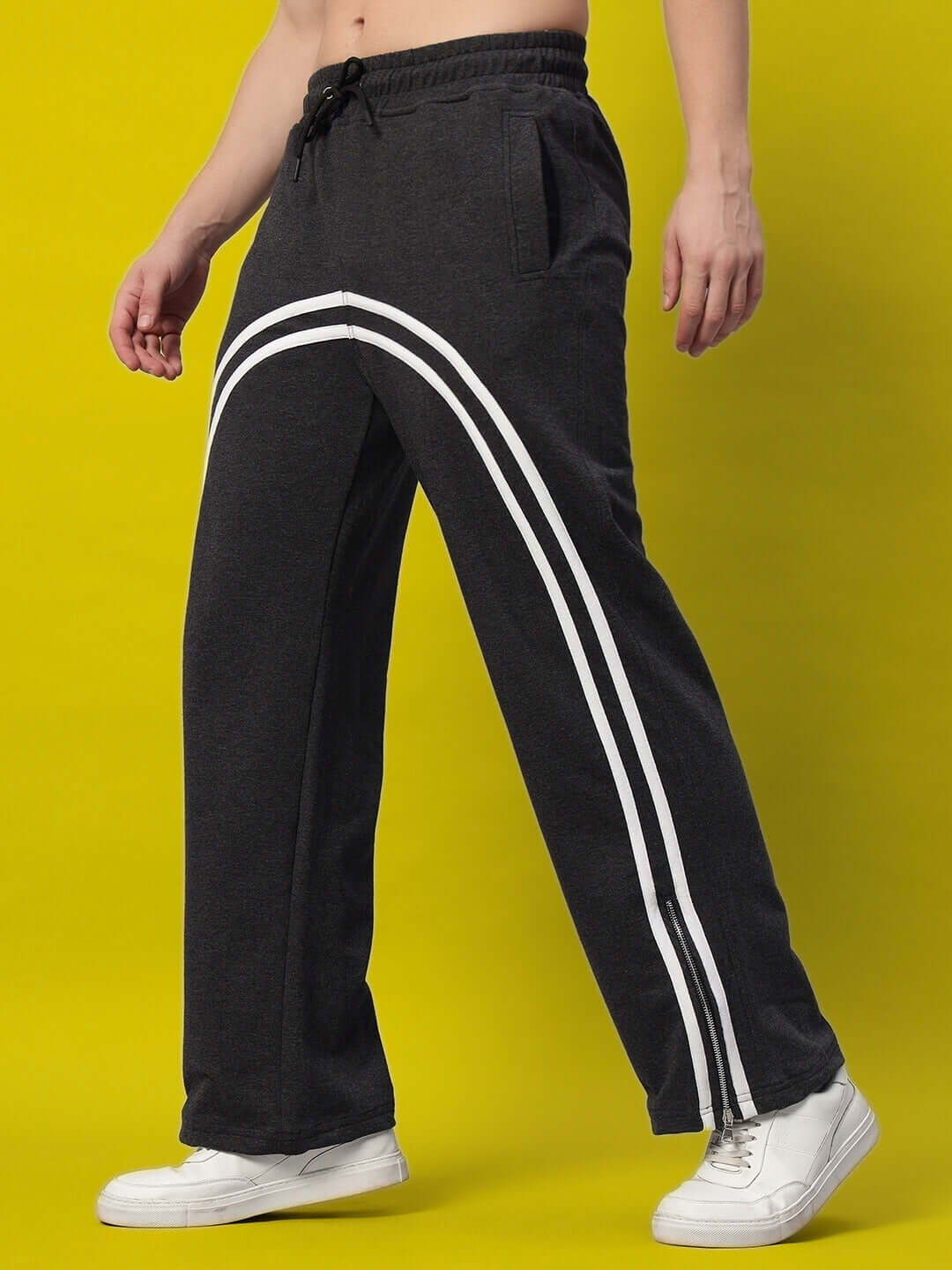 Dark grey BRONCO SLIT ZIPPER JOGGERS with side stripes, ideal for custom fit orders, crafted by DUDS' skilled tailors, worn with white sneakers.