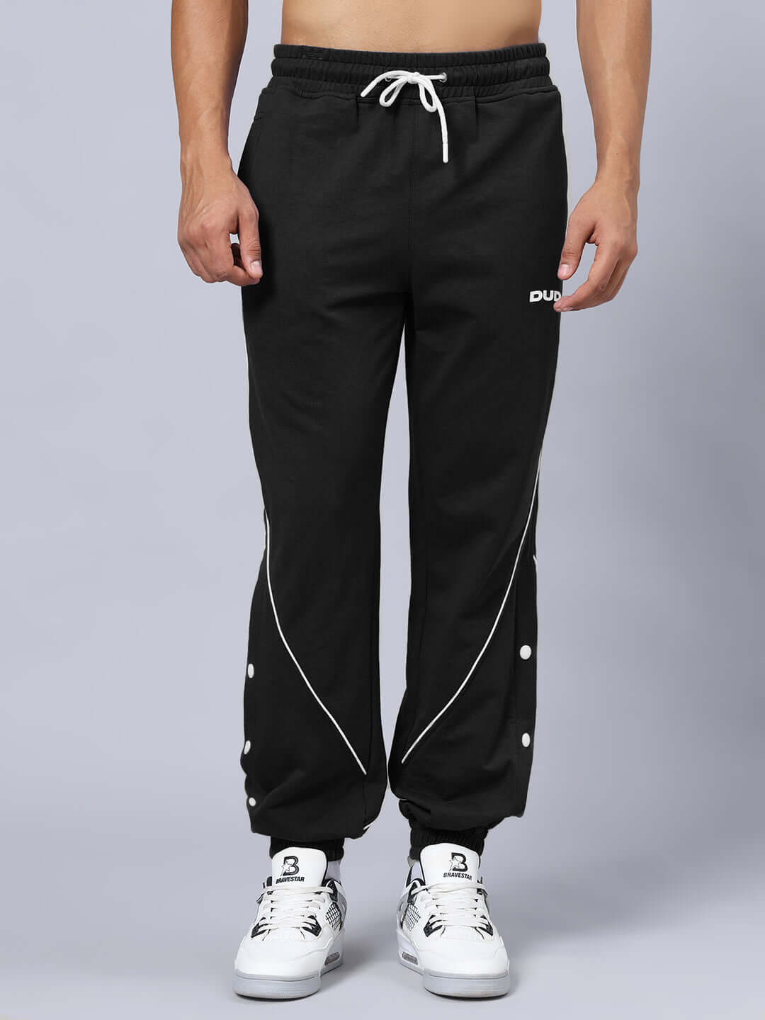 Model wearing BROSSFINE Contrast Joggers in black, featuring white piping and button details, customizable fit available, made by DUDS.